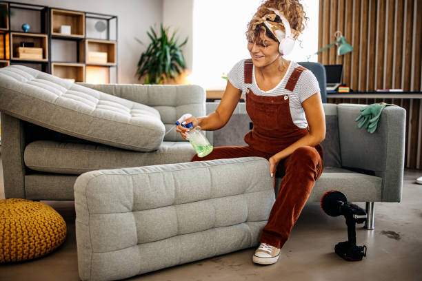 cleaner doing deep washing of sofa with professional equipment
